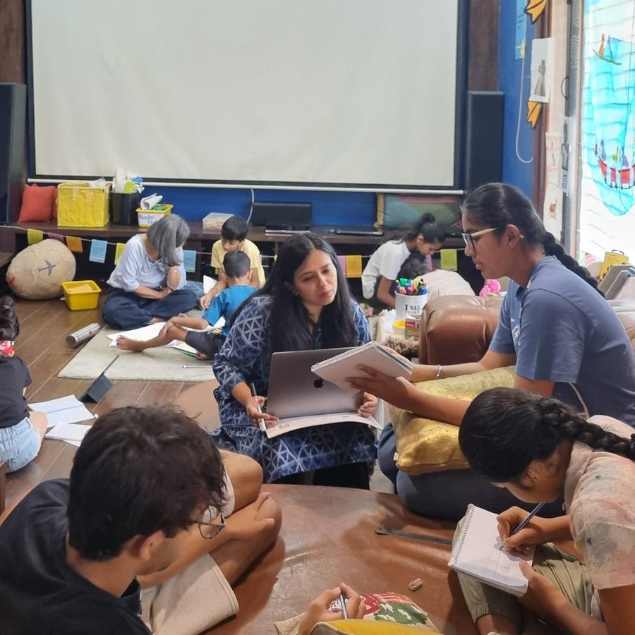 Children and facilitators working together on the floor with notebooks
