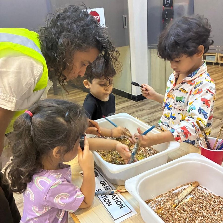 Children examining trays at an observation station with magnifying glasses