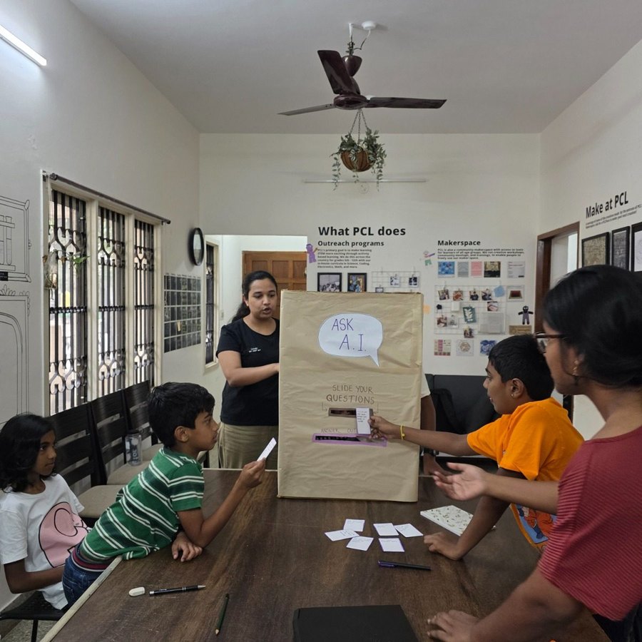 Children posting written questions into a cardboard Ask A.I. box
